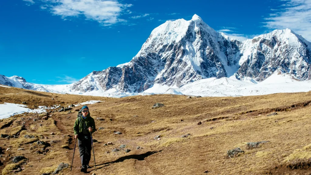 Hiker with trekking poles on the Ausangate trek below snowy peaks