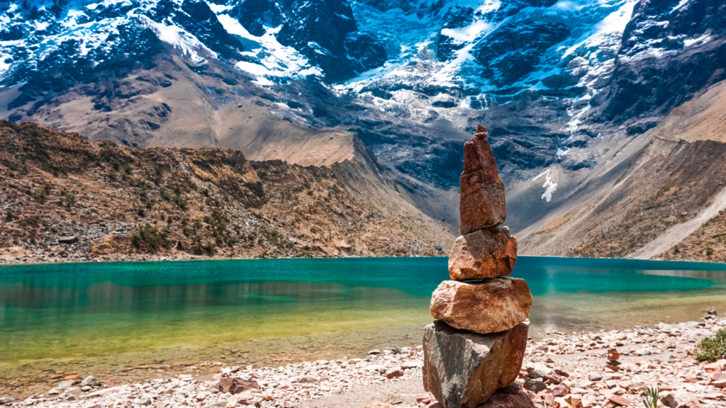 Stone cairn beside Humantay Lake below a snowcapped mountain