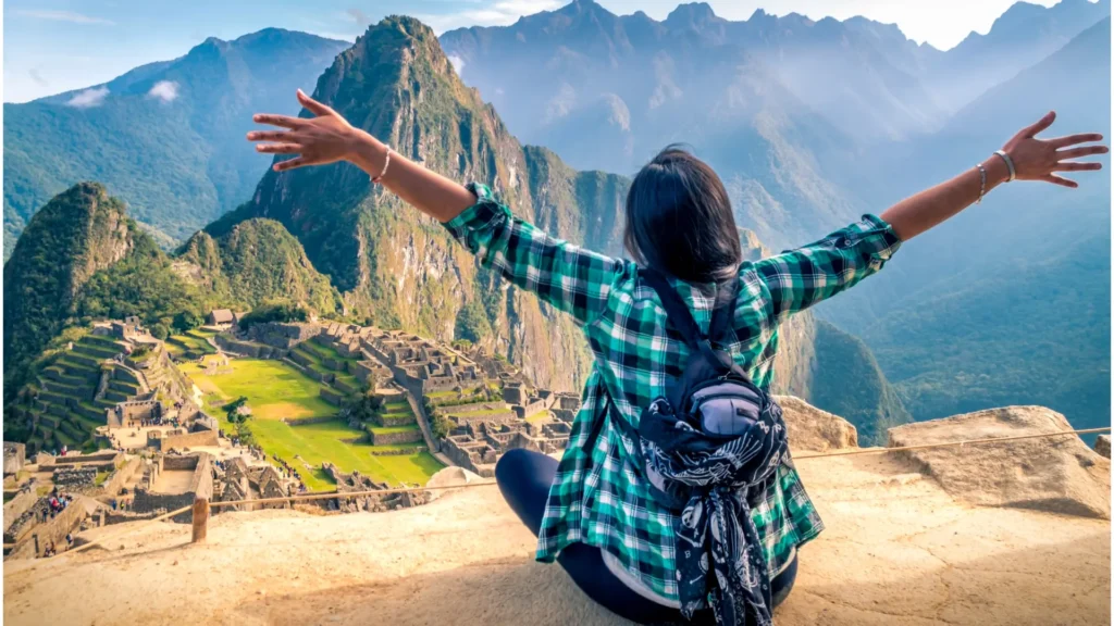 Traveler sitting with open arms in front of Machu Picchu