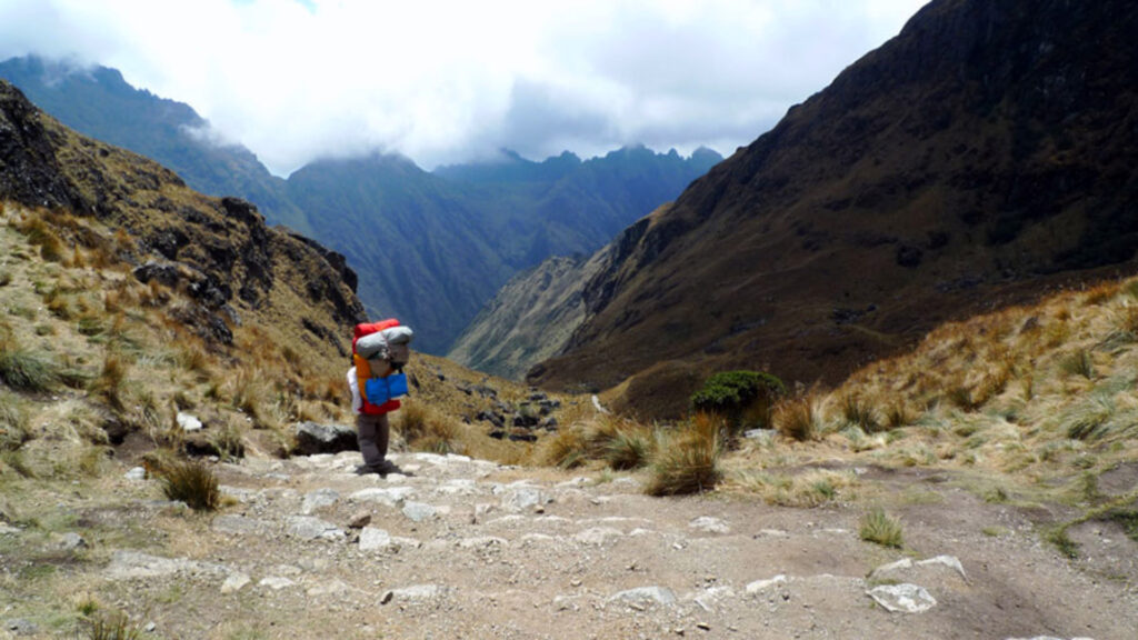 Hikers descending Warmiwañusca Pass with expansive valley views and rugged terrain