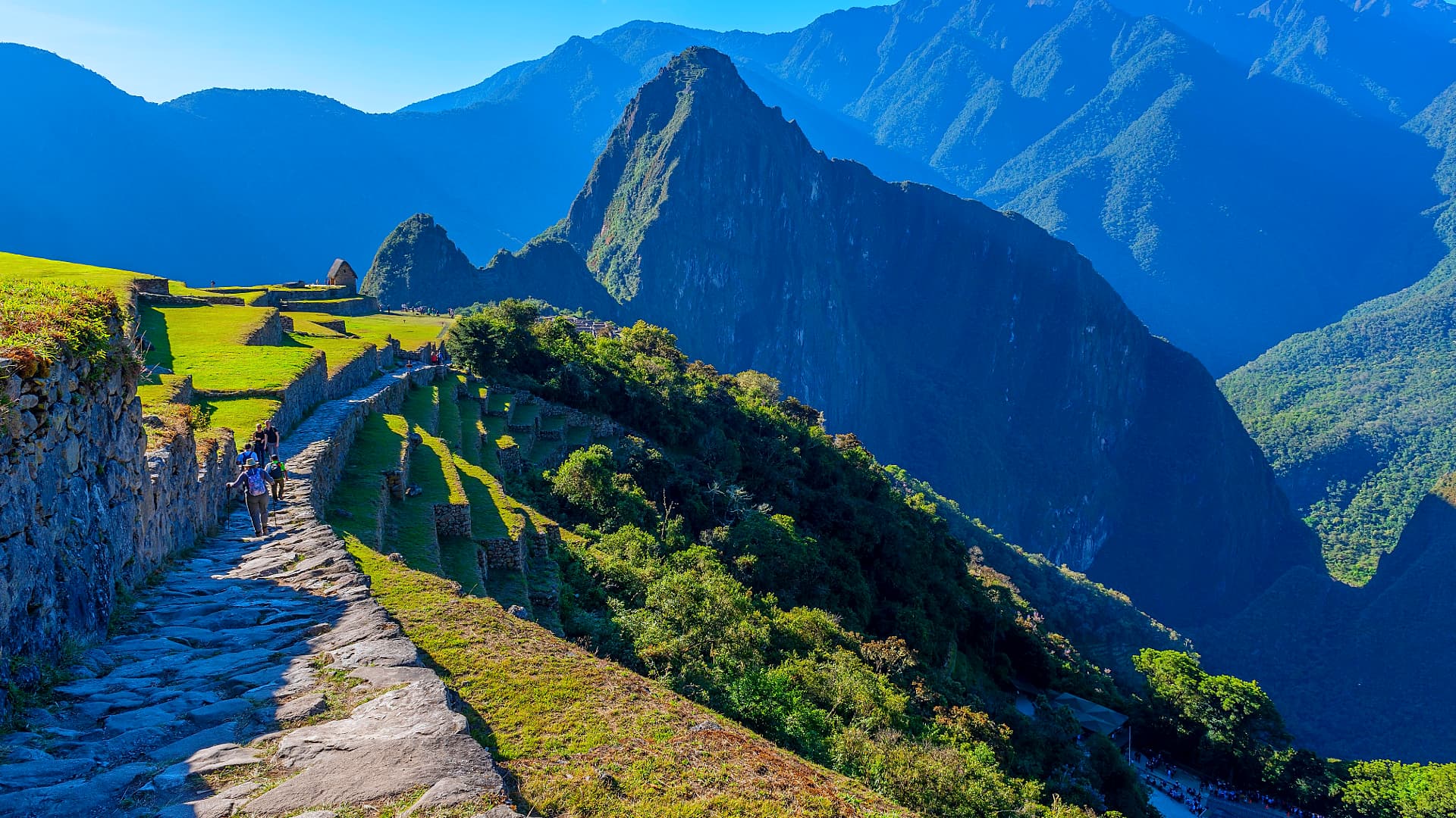 Hikers on an Inca stone path toward Machu Picchu with Huayna Picchu behind