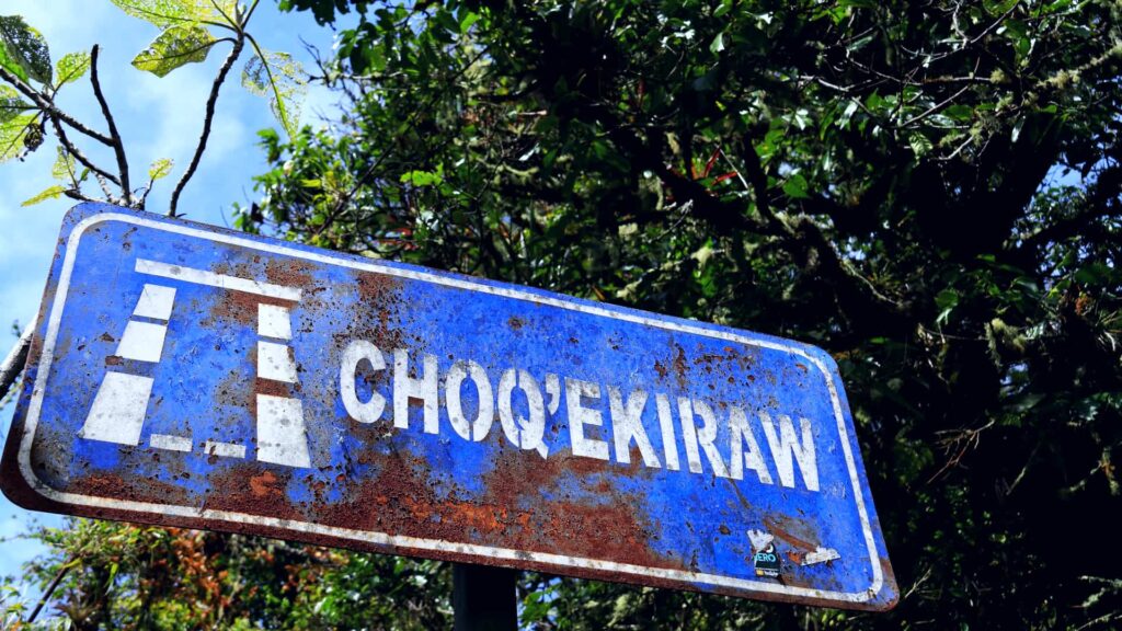 Rusty blue sign reading Choq'ekiraw among trees