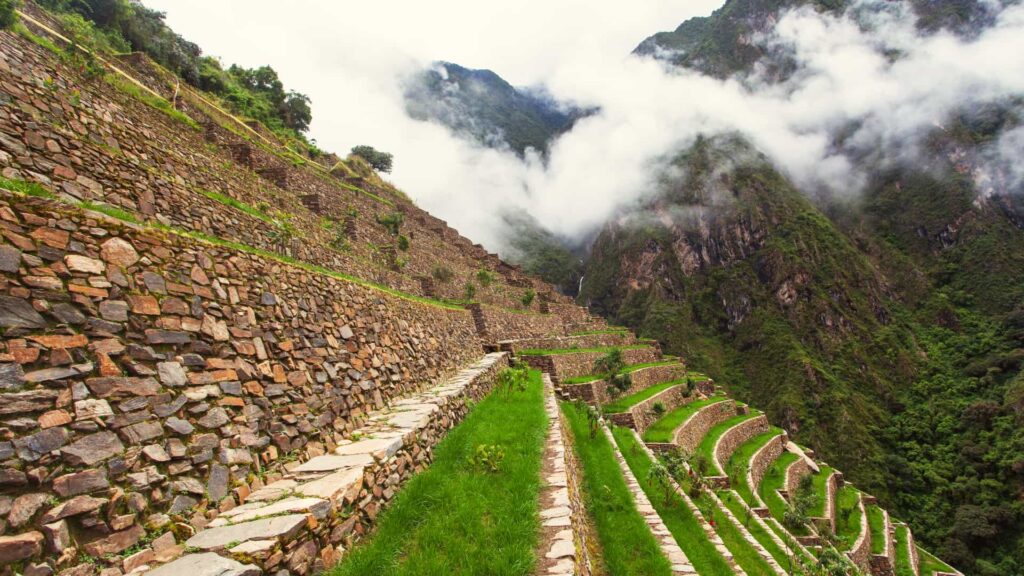 Stone terraces of Choquequirao above a cloud-filled canyon