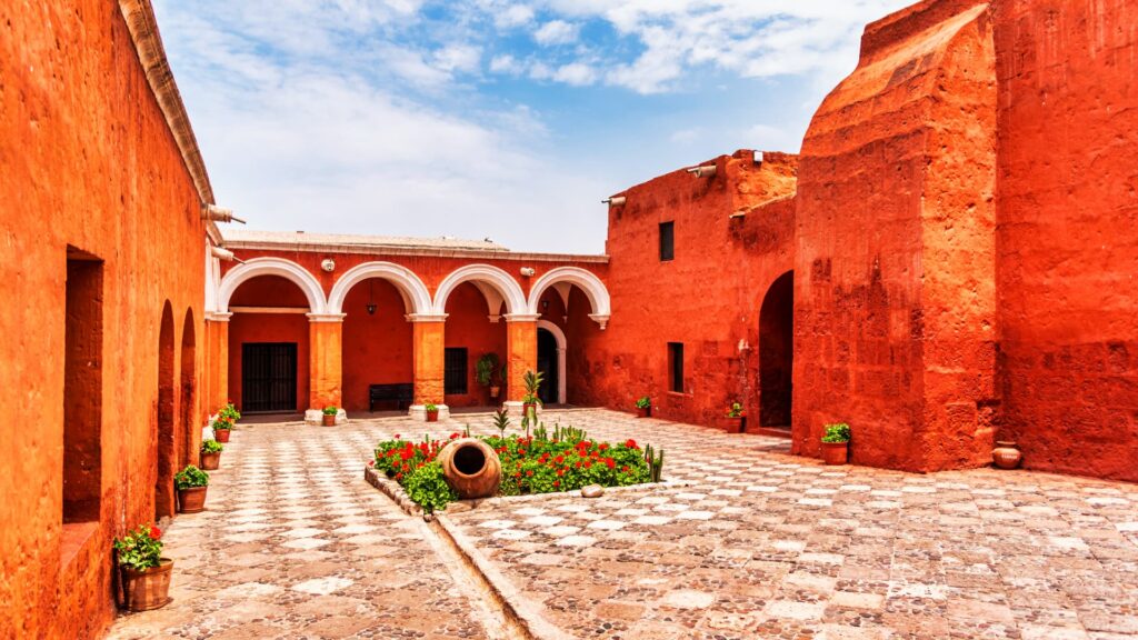 Red-walled courtyard with white arches at the Santa Catalina Monastery in Arequipa