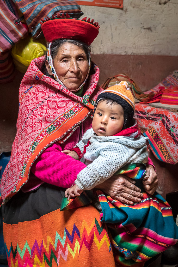 Woman from the Patacancha valley holding a baby, wearing her hand-woven lliclla shawl